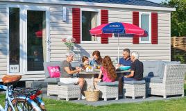 Famille déjeune sur la terrasse de son mobil home au camping de Oase