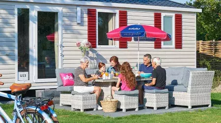 Famille déjeune sur la terrasse de son mobil home au camping de Oase